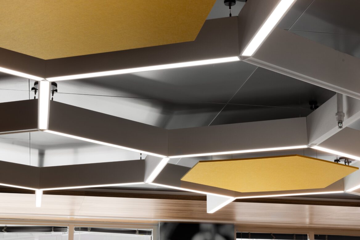 Geometric ceiling lights and yellow acoustic panels are suspended in a modern, minimalist interior with reflective surfaces.